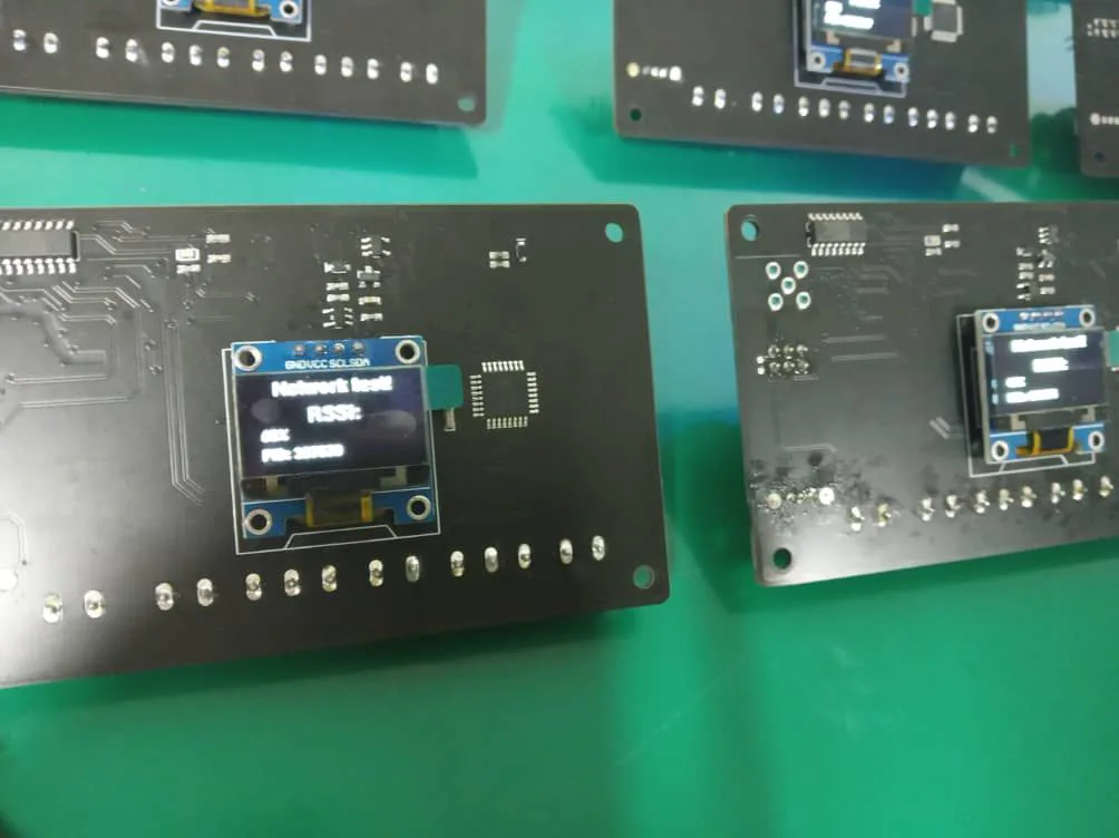 Close-up of custom LoRa boards with a network-test screen displaying RSSI